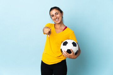 Young hispanic football player woman over isolated on blue background pointing front with happy expression