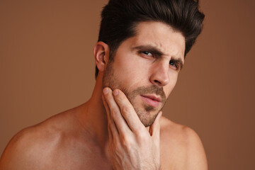 Obraz premium Brooding half-naked man looking at camera and rubbing his face