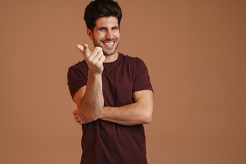 Obraz premium Joyful masculine man smiling and pointing finger at camera