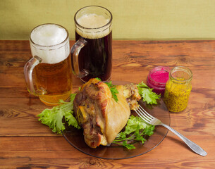 Baked ham hock, lager and dark beer on rustic table