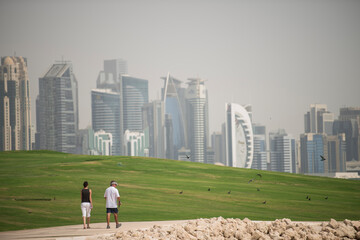 The couple walks through the park by the sea in the distance see the skyline in Doha,Qatar 04/28/2018 