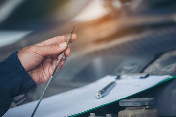 Car Mechanic man hand checking dipstick engine oil car mechanical on site service. Close up hand man check engine oil level Locate dipstick, wipe clean, check dipstick level before fill up engine oil