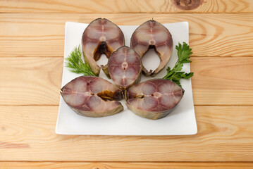 Sliced smoked Atlantic horse mackerel with greens on square dish