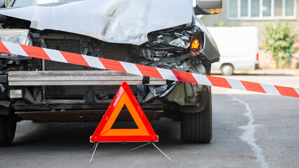 Red emergency stop triangle sign and Red warning police tape afore. Destroyed car in car crash traffic accident on city road. Smashed broken car in accident. Smashed broken headlight. Long web banner