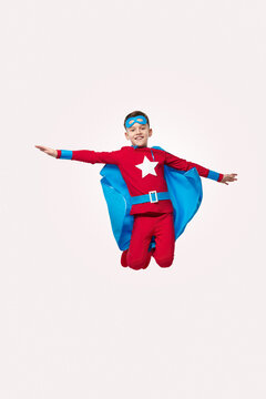 Brave Kid In Superhero Costume Jumping In Studio