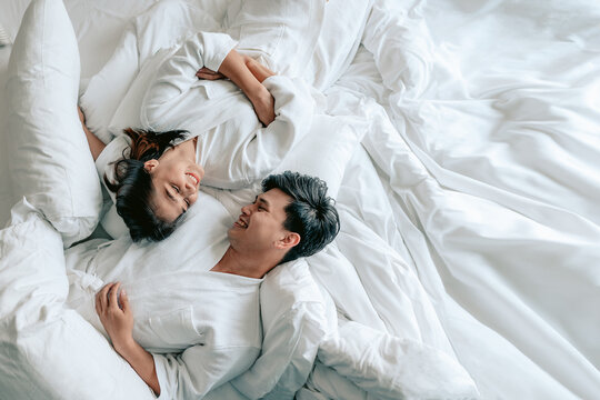 Asian couples is laying on bed in the bed room at modern home.Couple in Valentine day.Love couple,Relationship and couple concept.
