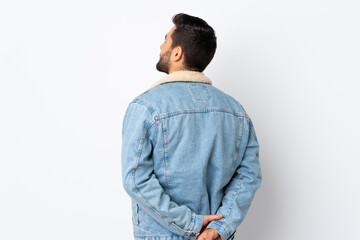 Young handsome man with beard isolated on white background in back position and looking back