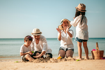 Happy parents and kid having fun with playing sand in summer vacation on the beach.Travel,Happy...
