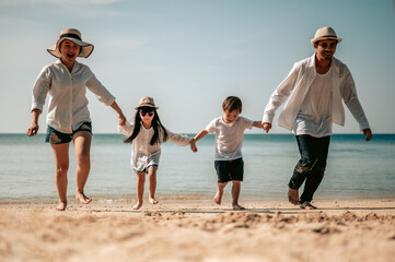 Happy asian family, Parents are holding hands their children and walking on the beach in holiday.Family, travel, beach, relax, lifestyle, holiday concept.