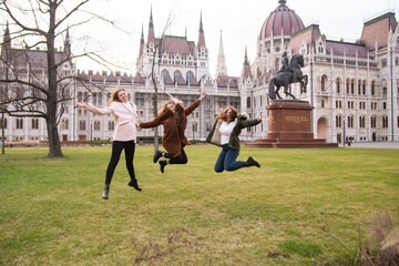 Fototapeta premium Travel to Hungary, European tour. Tourists - Girls and a guy near the Hungarian parliament. A group of people are traveling across Europe.