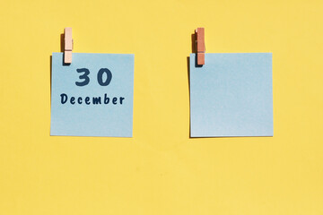 30 December. 30th day of the month, calendar date. Two blue sheets for writing on a yellow background. Top view, copy space. Winter month, day of the year concept