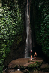 Lovers at the waterfall. Couple admiring a beautiful waterfall in Indonesia. Couple on vacation in Bali. Honeymoon trip. The couple is traveling in Asia. Vacation on the island of Bali with copy space
