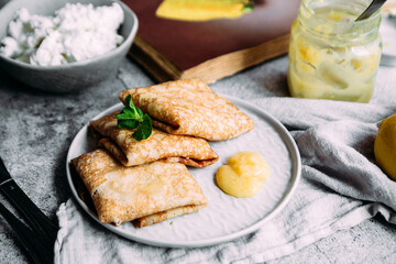 Crepes with homemade cottage cheese and lemon curd on a gray plate