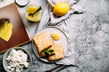 Crepes with homemade cottage cheese and lemon curd on a gray plate