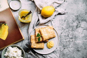 Crepes with homemade cottage cheese and lemon curd on a gray plate