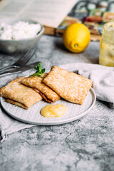 Crepes with homemade cottage cheese and lemon curd on a gray plate