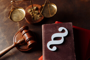 White paragraph symbol is on law book and gavel in courtroom. Top view