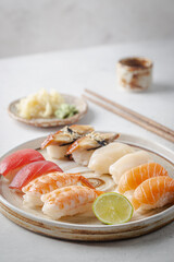 Set of sushi and maki on plate with soy sauce and chopsticks on white background. Top view with copy space