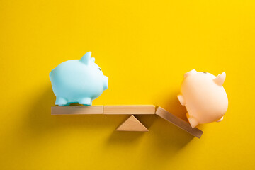 Piggy bank balancing on seesaw on yellow background
