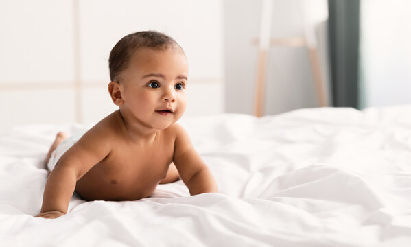 Cute little African American baby lying on bed