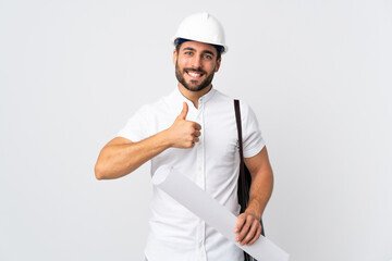 Young architect man with helmet and holding blueprints isolated on white background giving a thumbs up gesture