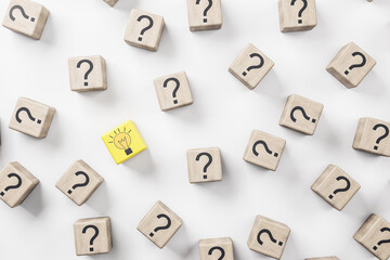 Idea concept with wooden cubes with question sign and one yellow with light bulb on white background