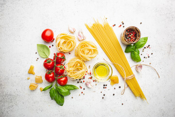 Pasta background. Several types of dry pasta with vegetables and herbs on white background. Free space for text. Top view