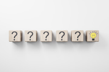 New idea concept with row of wooden cubes with question mark and one with yellow light bulb