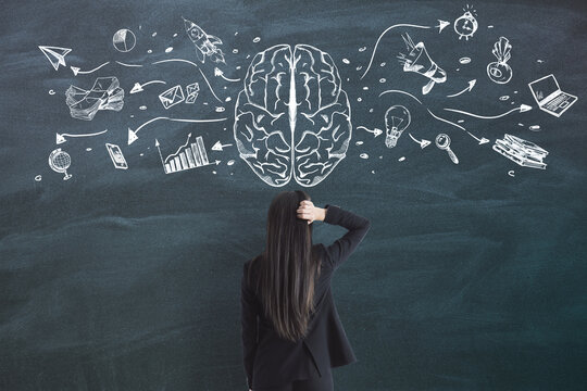 Creative business idea concept with young lady looking at the blackboard with sketch of brain and business icons