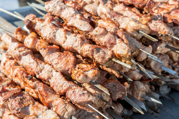 Street food. Delicious shish kebab cooked in a grill on hot coals is sold outdoors.