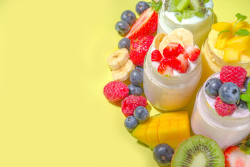 Set of various fruit and berry sweet yogurts in glass jars. Variety healthy Breakfast yoghurts with blueberry, strawberry, mango, kiwi, raspberry, with fresh fruits and berries