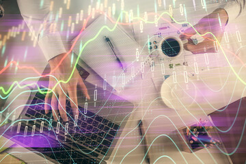 Multi exposure of man's hands typing over computer keyboard and forex graph hologram drawing. Top view. Financial markets concept.