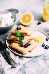Crepes with homemade cottage cheese, blueberries and lemon curd on a gray plate