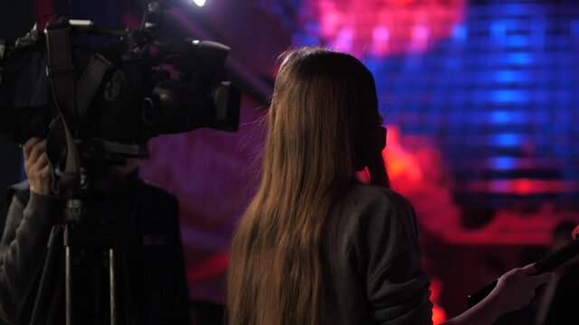 The journalist and cameraman are interviewed in a large stadium. Amid the interview is a huge scene with rows of chairs
