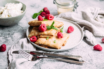 Crepes with homemade cottage cheese, raspberries a gray plate