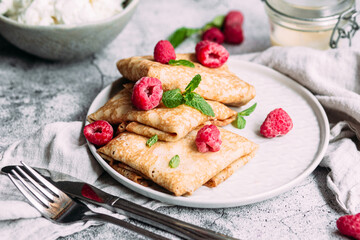 Crepes with homemade cottage cheese, raspberries a gray plate
