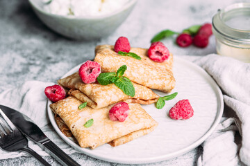 Crepes with homemade cottage cheese, raspberries a gray plate