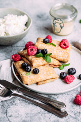 Crepes with homemade cottage cheese, raspberries a gray plate