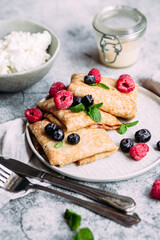 Crepes with homemade cottage cheese, raspberries a gray plate