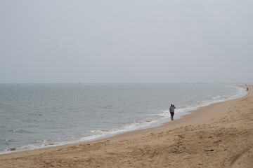 Fototapeta na wymiar people walking along sand beach on sunny day. Holiday beach in Haikou city, Hainan province