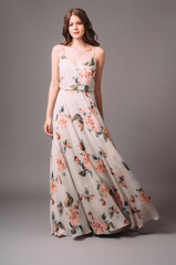Candid portrait of a brunette young woman in summer gown with shoulder straps and floral print....