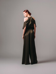 Confident ginger woman in dark silk jumpsuit. Women’s clothing, fashionable gown, halter dress....