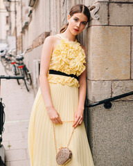 Young brunette woman in yellow evening dress with golden handbag. Female bright look, lemon glamour...