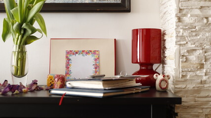 Komódka mebel w salonie z ramką czerwoną, karteczką kolorową i lampką szklaną bordową