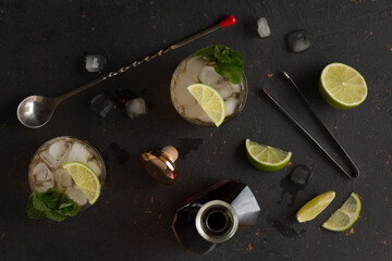 Alcoholic cocktail with rum and ice and mint on a dark background in a bar