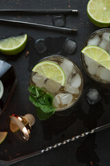 Alcoholic cocktail with rum and ice and mint on a dark background in a bar