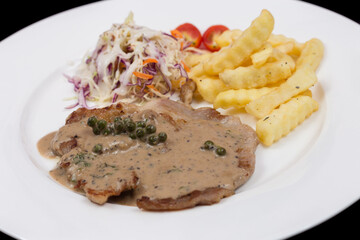 Steak with pepper sauce serve with french fries and salad.