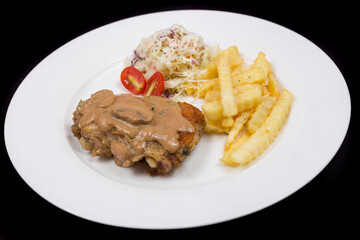 Steak with mushroom sauce, french fries and salad on plate.