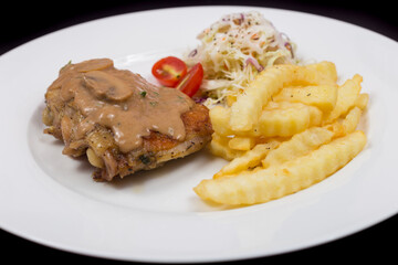 Steak with mushroom sauce, french fries and salad on plate.