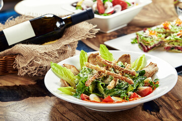 Caesar salad with bread sticks, quail eggs, cherry tomatoes and grilled chicken in plate on white background
